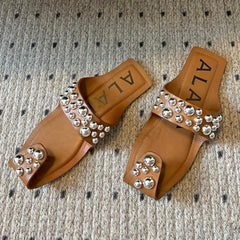 ALAIA FOLDED FLAT MULES WITH SPHERES ON COPPER BROWN CALFSKIN