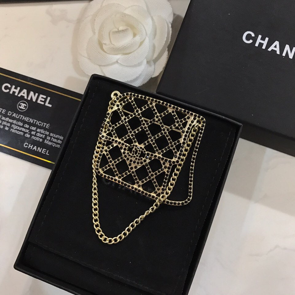 BAG SHAPED BROOCH IN GOLD METAL WITH BLACK CRYSTAL