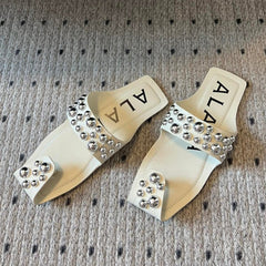 ALAIA FOLDED FLAT MULES WITH SPHERES ON WHITE CALFSKIN